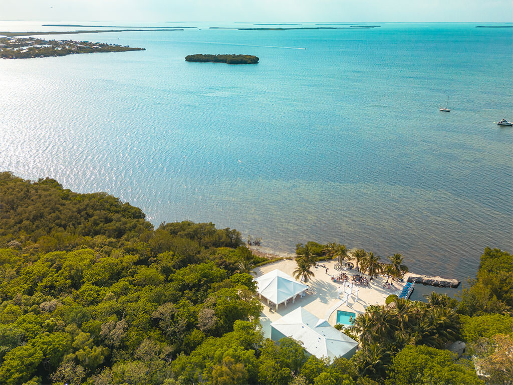 Aerial view of a beach wedding ceremony at Key Largo Lighthouse, one of the best Florida destination weddings venues.